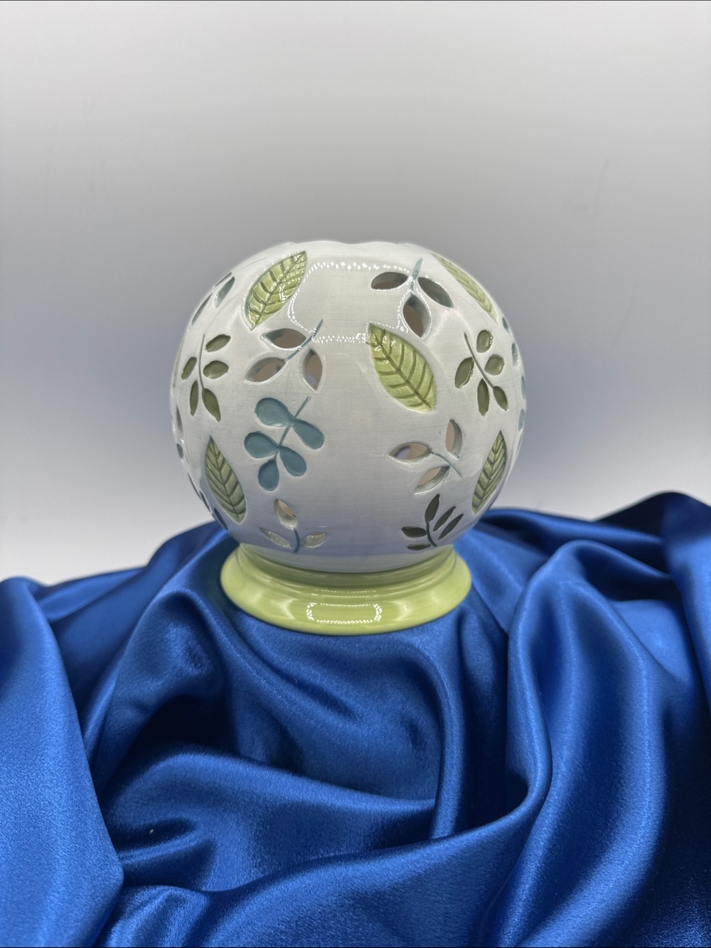 Ceramic illuminated globe/base featuring a pierced or cut-out floral design.